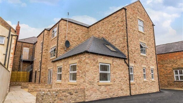 A two-story brick building with multiple windows and a sloped roof. - Fabulous Apartment in the City of Ripon, close to Cathedral with private parking (Ripon)