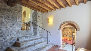 Eine Steintreppe mit Holzboden, die zu einem Raum mit einem gemusterten Wand und einem roten Sofa führt.