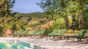 Ein Poolbereich mit Liegestühlen und freiem Blick auf die umliegende Landschaft.