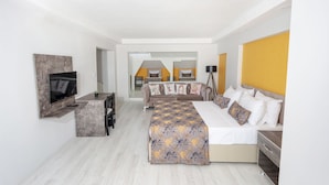 Une chambre d’hôtel avec un grand lit, un téléviseur fixé au mur, un bureau et un canapé.