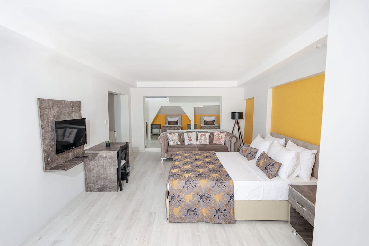 Une chambre d’hôtel avec un grand lit, un téléviseur fixé au mur, un bureau et un canapé.
