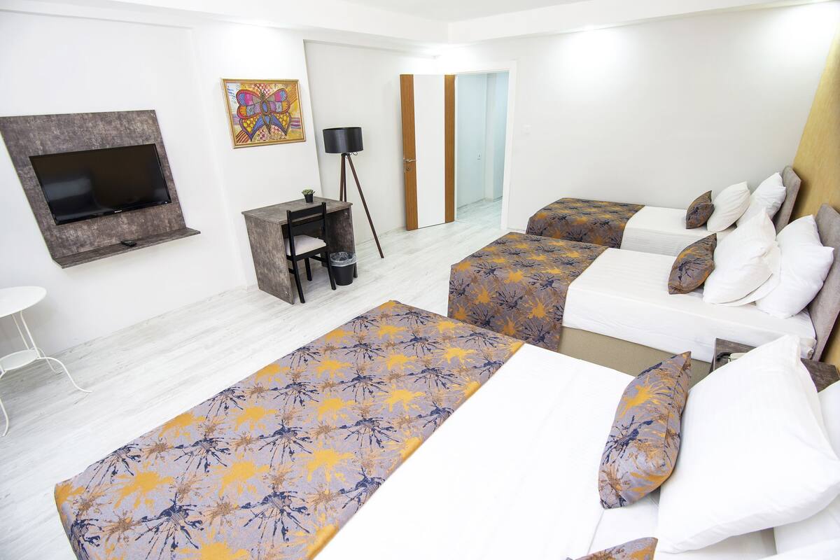 Une chambre d’hôtel avec deux lits, un bureau, une télévision et un miroir.
