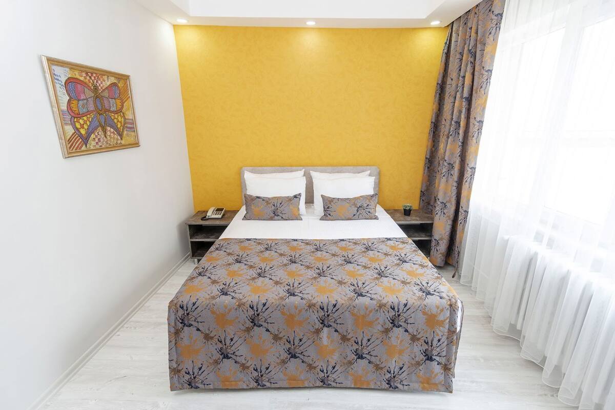 Une chambre d’hôtel avec un lit, une table de chevet, un téléphone et un tableau au mur.
