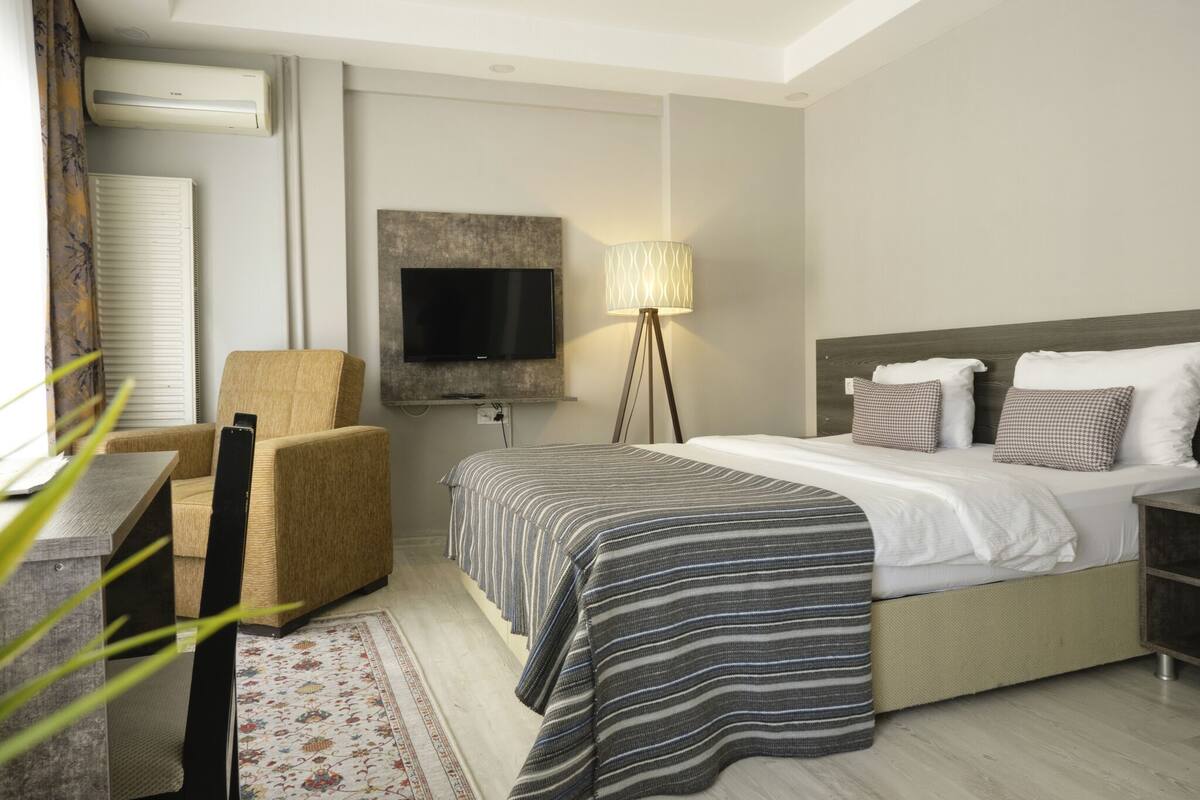 Une chambre d’hôtel avec un lit, une chaise, une télévision et une lampe.