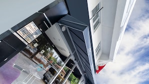 Un hôtel moderne, reconnaissable à son auvent noir bien visible et à un drapeau rouge qui flotte sur le toit.