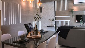 A modern kitchen with wooden paneling, pendant lighting, a dining table with chairs, and a sofa. - Kenwingston Square Garden by IdealHub (Cyberjaya)