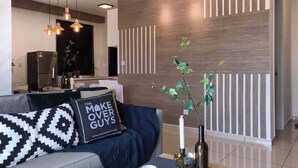 A modern living room with a sofa, a coffee table, and a decorative plant. - Kenwingston Square Garden by IdealHub (Cyberjaya)