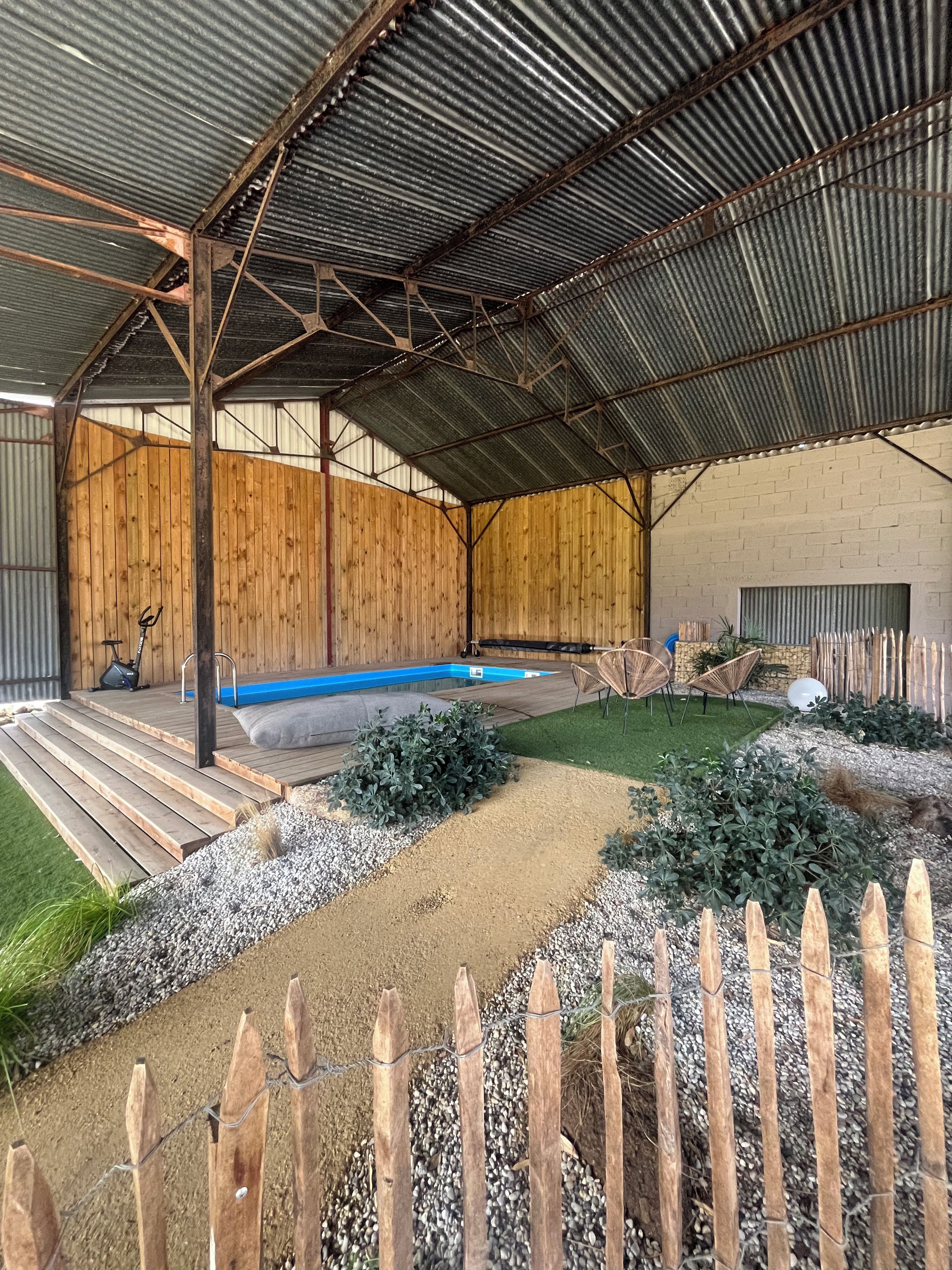 Un espace extérieur abrité comprenant une piscine, des marches en bois et un jardin clôturé.