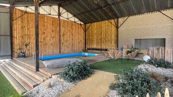 Un espace extérieur abrité comprenant une piscine, des marches en bois et un jardin clôturé.
