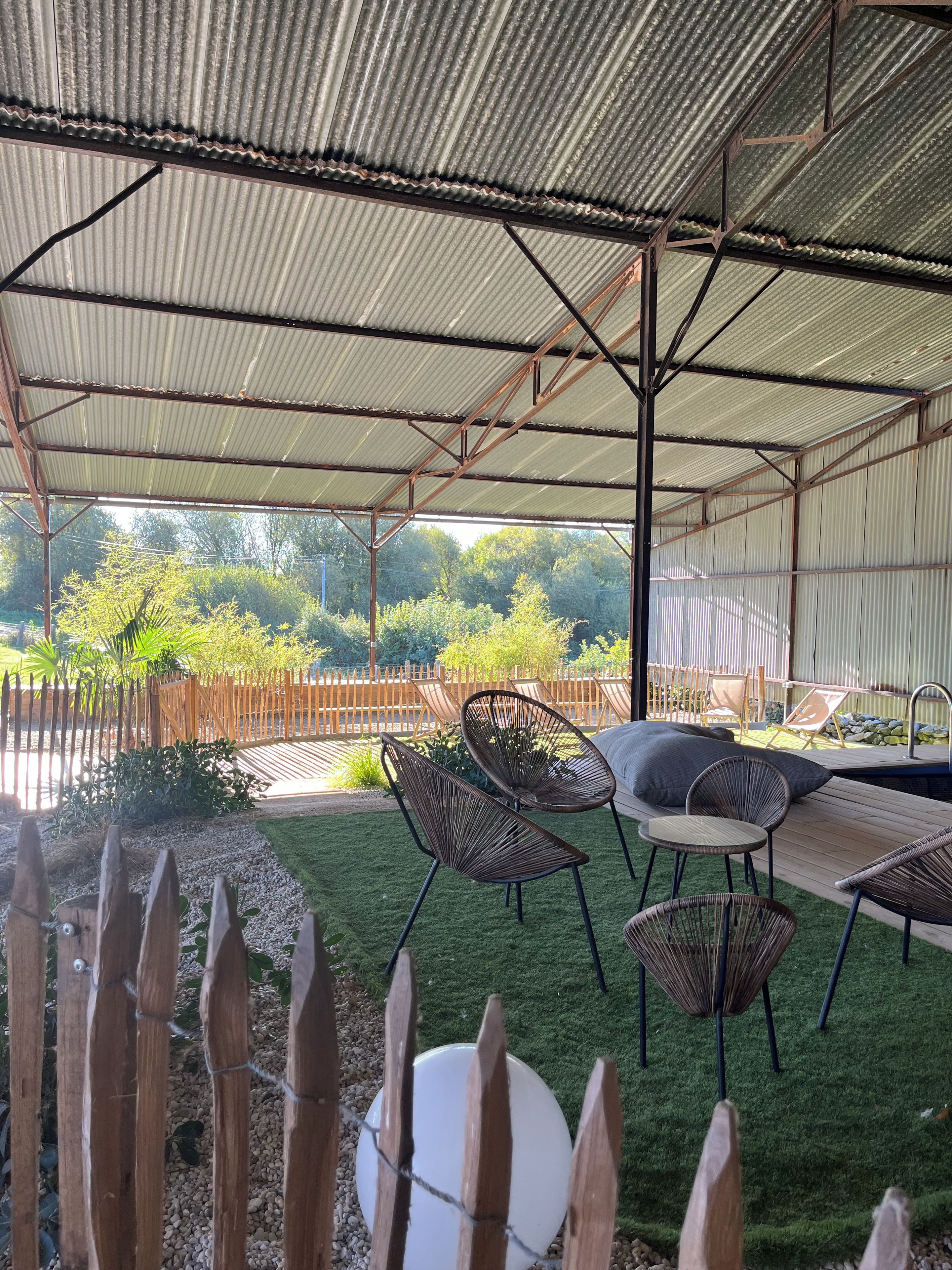 Un patio extérieur couvert avec un toit en métal, une piscine et du mobilier d’extérieur.