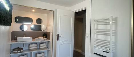 A hallway with a white door, a radiator, and a small potted plant.