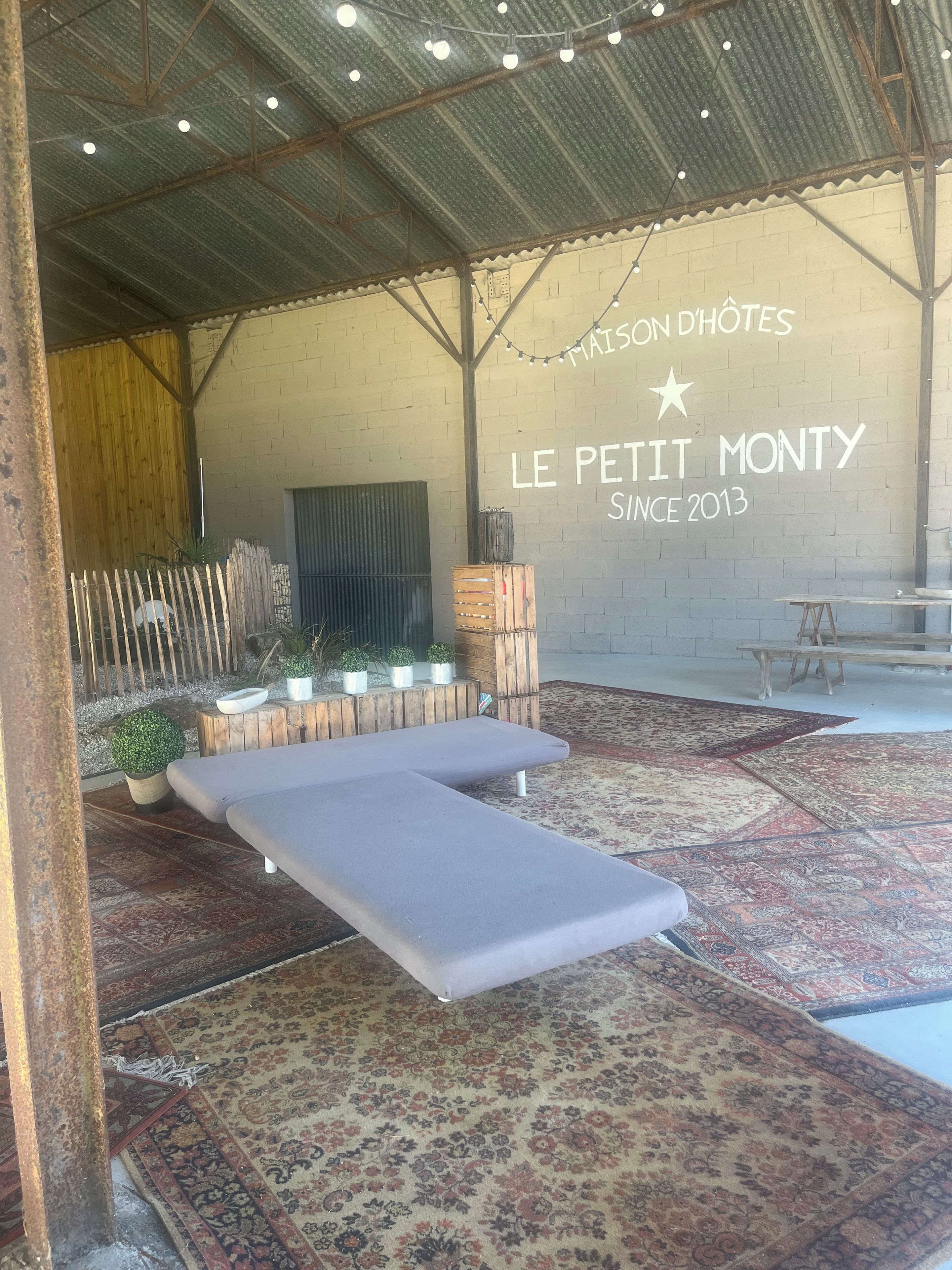 Un intérieur chaleureux avec un lit, un banc et un mur orné d’une enseigne.