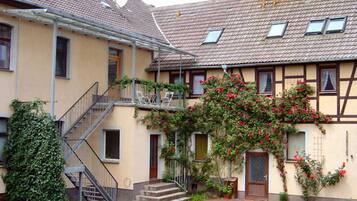 Ein zweistöckiges Gebäude mit Balkon, Treppe und Garten.