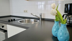 Een keuken met een zwart aanrecht, een roestvrijstalen spoelbak en twee blauwe vazen met witte tulpen.
