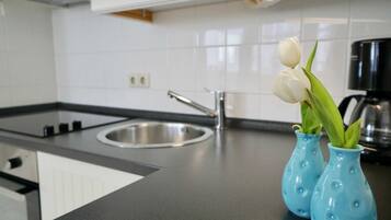 Eine Küche mit schwarzem Arbeitsplatz, einer Edelstahlspüle und zwei blauen Vasen mit weißen Tulpen.