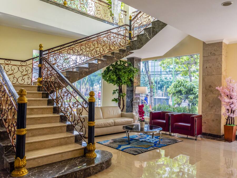 A lobby with a marble staircase, a sofa, a coffee table, and a large window with a view of greenery.
