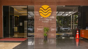 The entrance of the Sunbreeze Hotel with a clear glass facade, a potted plant, and a red mat at the entrance. - Sunbreeze Hotel Senayan (Jakarta)