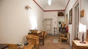 A cozy dining area with wicker furniture, a tiled floor, and a door leading to another room. - Agriturismo Case Perrotta (Sant'Alfio)