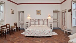 A bedroom with a bed, two chairs, a small table, and a nightstand. - Agriturismo Case Perrotta (Sant'Alfio)