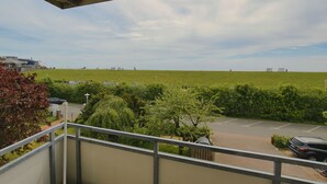A balcony with a view of a parking lot and a grassy field. - N 8K (BC.a5) - Stranddomicil Steiner (Büsum)