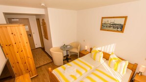 Habitación de hotel con cama, escritorio con una computadora portátil, silla, mesita y armario.