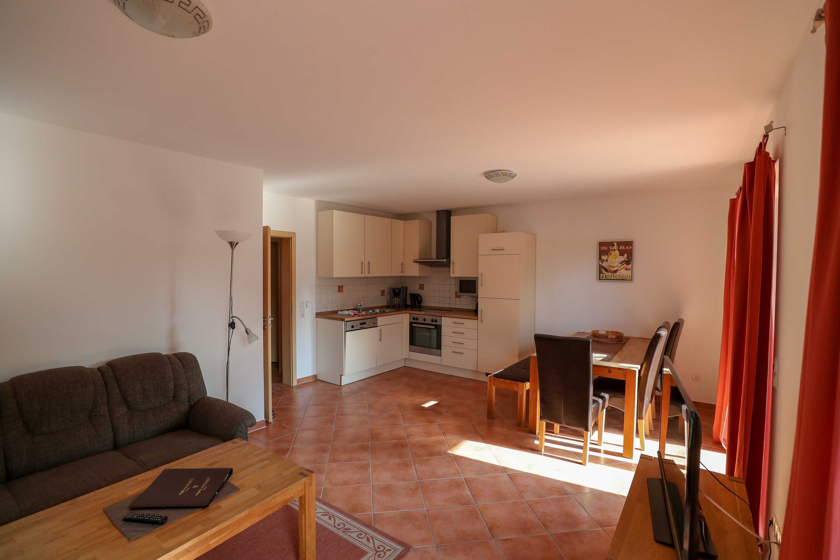 Een knus woongedeelte met een kitchenette, een eethoek en een bank.