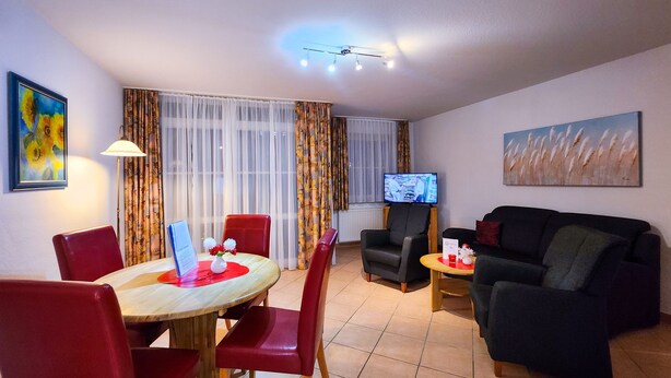 A living room with a dining area, a TV, and a painting on the wall.