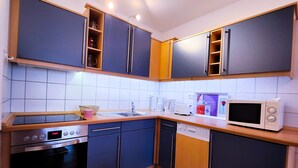 A modern kitchen with blue cabinets, a microwave, a coffee maker, and a dishwasher.