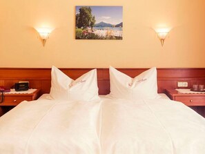 Ein Hotelzimmer mit einem Bett, zwei Nachttischen, einer Wandlampe und zwei Wandleuchten sowie einem Wandbild.