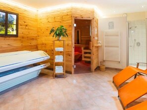 L’intérieur d’une cabane en bois comprend un lit, une douche et une échelle en bois sur laquelle sont posées des serviettes.