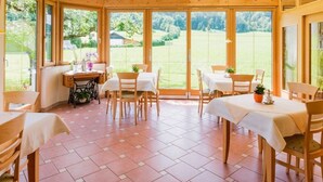 Une véranda avec des poutres en bois, de grandes fenêtres et un sol carrelé.