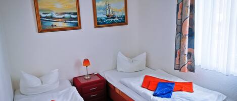 Una habitación de hotel con dos camas, una mesita de noche y dos cuadros en la pared.