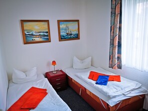 A hotel room with two beds, a nightstand, and two paintings on the wall. - 3 room A + 2 - Wohnpark Binz (with indoor pool) (Binz)
