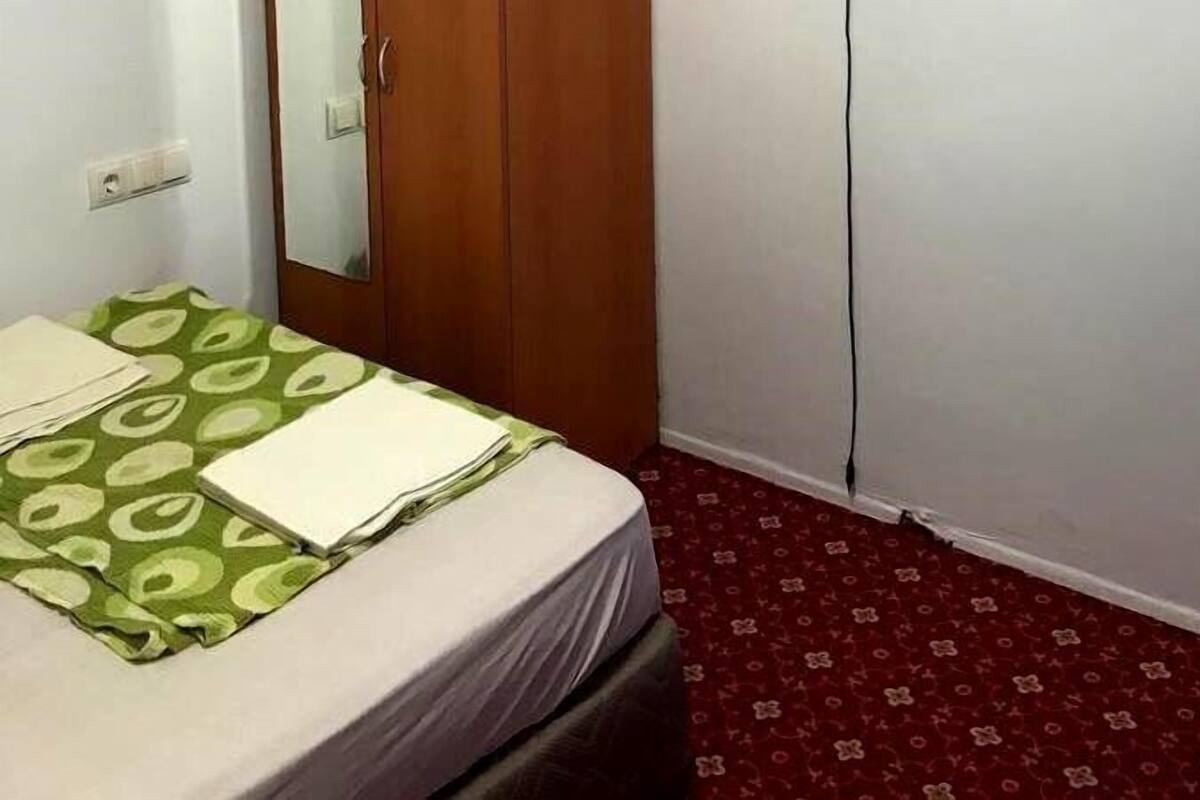 Ein Hotelzimmer mit einem Bett, einem Holzschrank und einem roten Teppich mit Muster.
