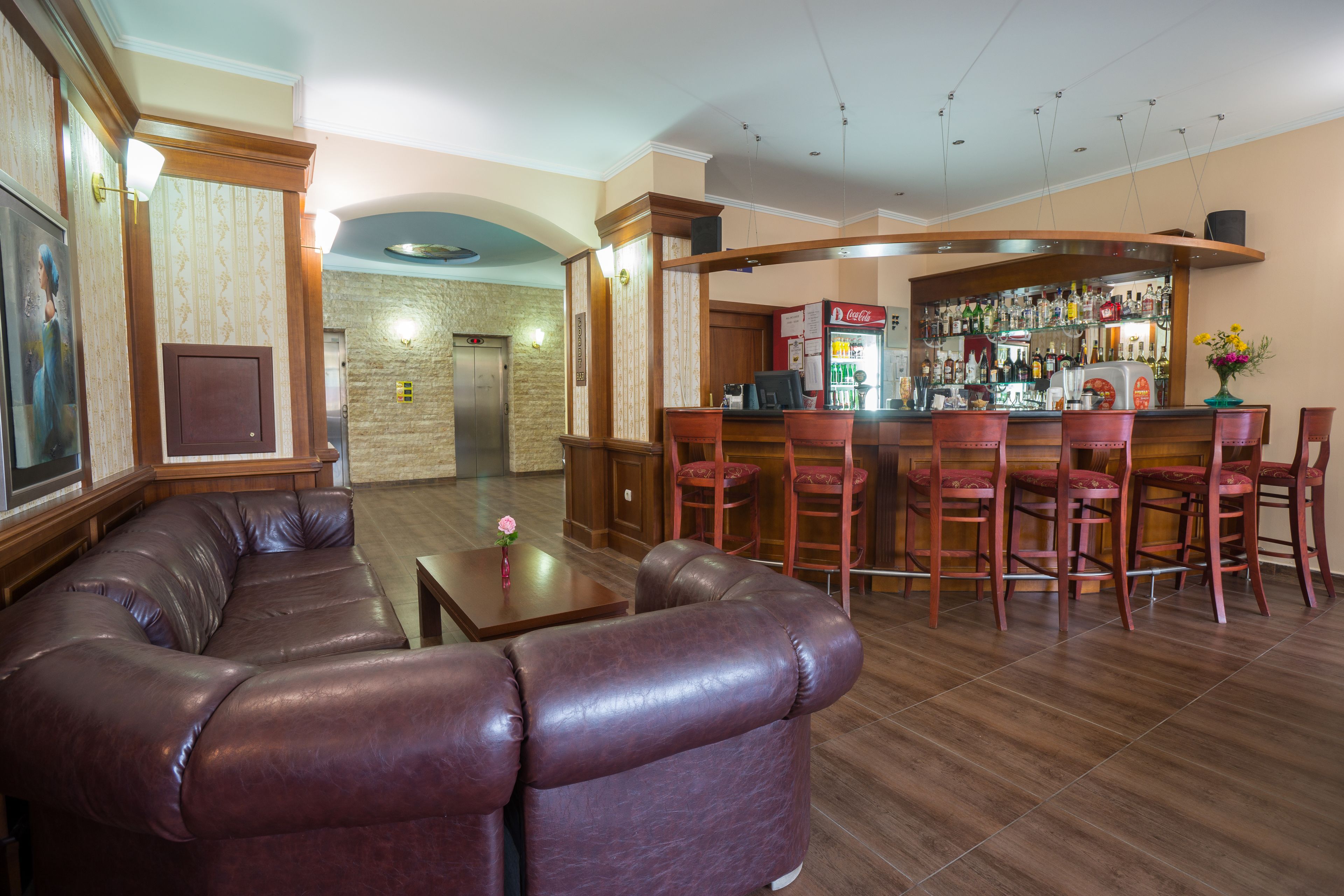 A bar area with leather seating and a bar counter stocked with various beverages.