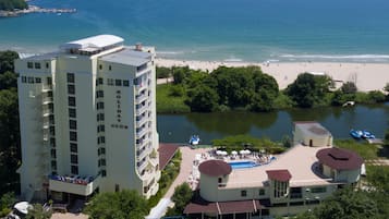 A hotel with a pool, beach, and lake view.