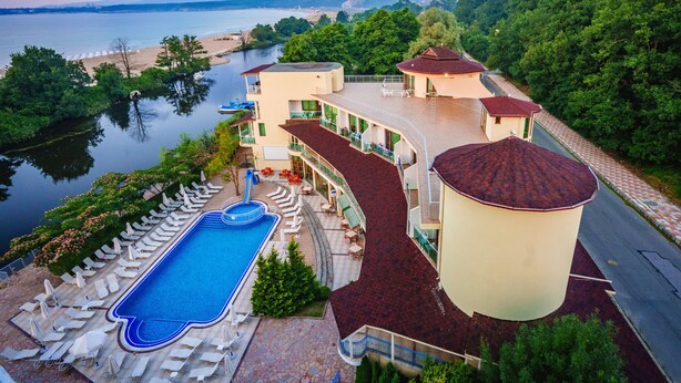 A resort with a swimming pool, lounge chairs, and a view of the lake and mountains. - Perla Sun Park Hotel (Primorsko)