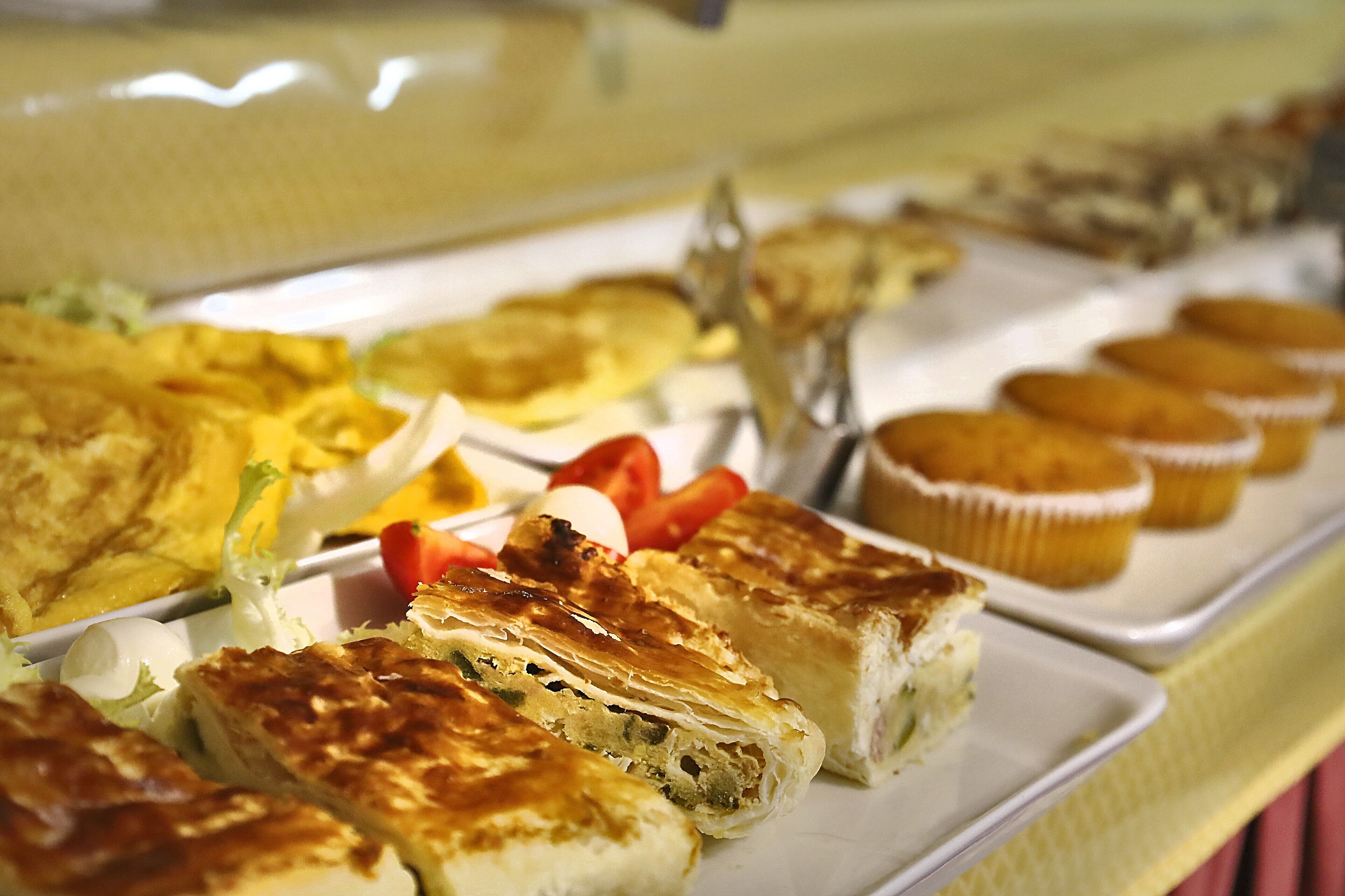 En buffet med forskellige retter, herunder bagværk, salater og frugt.