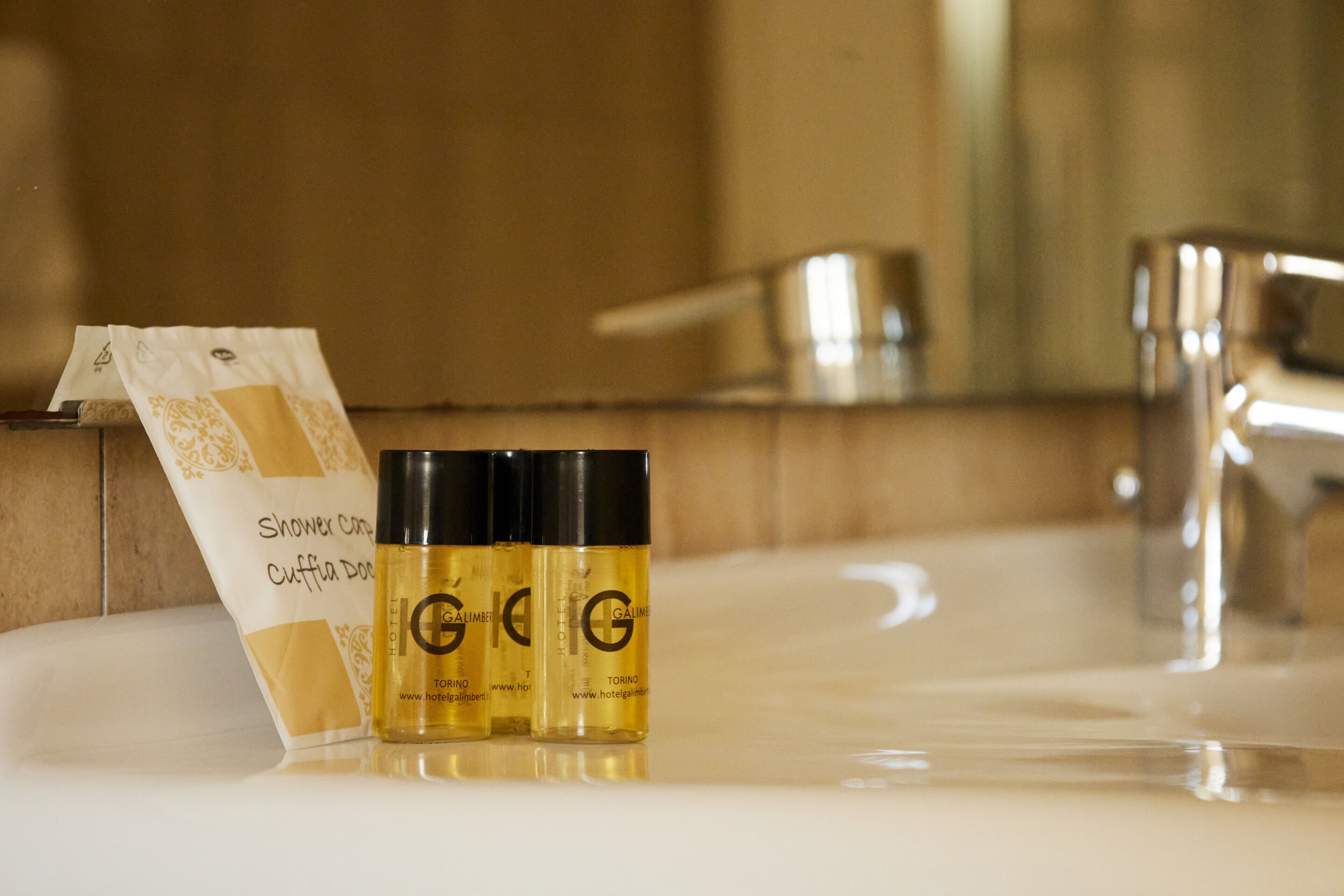 A bathroom with a sink, a mirror, and three bottles of shower cream.
