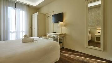 Una habitación de hotel con una cama grande, un escritorio, una televisión, un espejo y una ventana con cortinas.