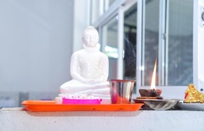 A white Buddha statue on a pedestal with a lit candle and incense. - Nature Life Guest Inn (Ella)