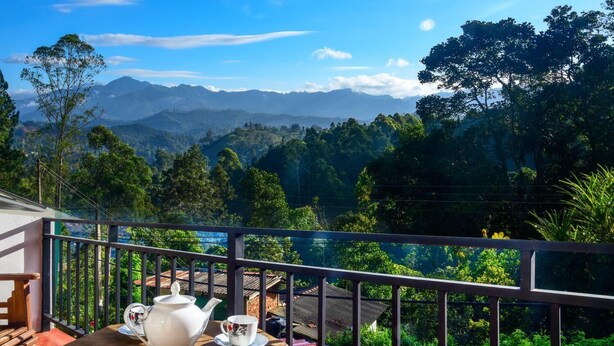 A balcony with a table set for tea, overlooking a mountainous landscape. - Nature Life Guest Inn (Ella)