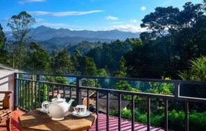 A balcony with a table set for tea, overlooking a mountainous landscape. - Nature Life Guest Inn (Ella)