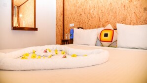A hotel room with a neatly made bed, a wooden headboard, a bedside table with a water bottle, and a mirror on the wall. - Nature Life Guest Inn (Ella)