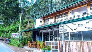 A two-story building with a covered outdoor seating area, wooden furniture, and potted plants. - Nature Life Guest Inn (Ella)
