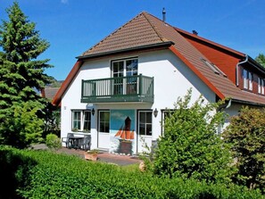 A two-story house with a balcony, a small garden, and a mural of a sailboat on the front wall. - 14 double rooms - DEB 006 Pension Seeperle (Sellin)