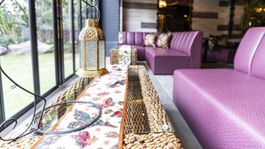Een modern interieur met een paarse bank, een tafel met patroon en uitzicht op groen buiten.