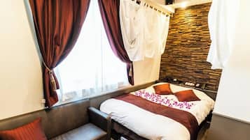 A modern hotel room with a bed, a bench, and a stone wall.