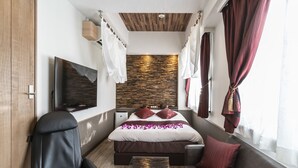 Een moderne hotelkamer met een bed, een televisie, een bank en een bureau.
