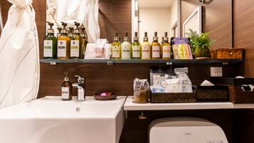 A bathroom with a white sink, a mirror, and a shelf with various toiletries.